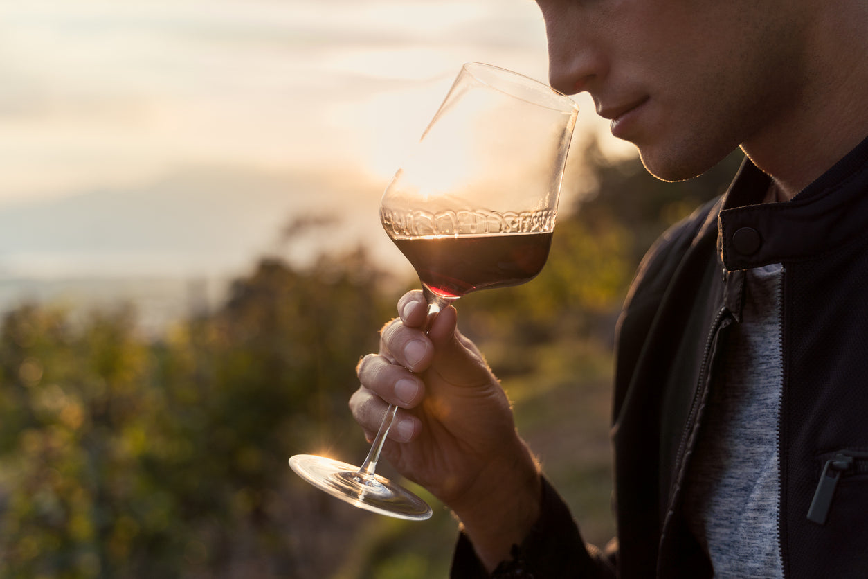 Mann genießt Rotwein aus edlem Weinglas im Sonnenuntergang, stilvolle Küchenaccessoires