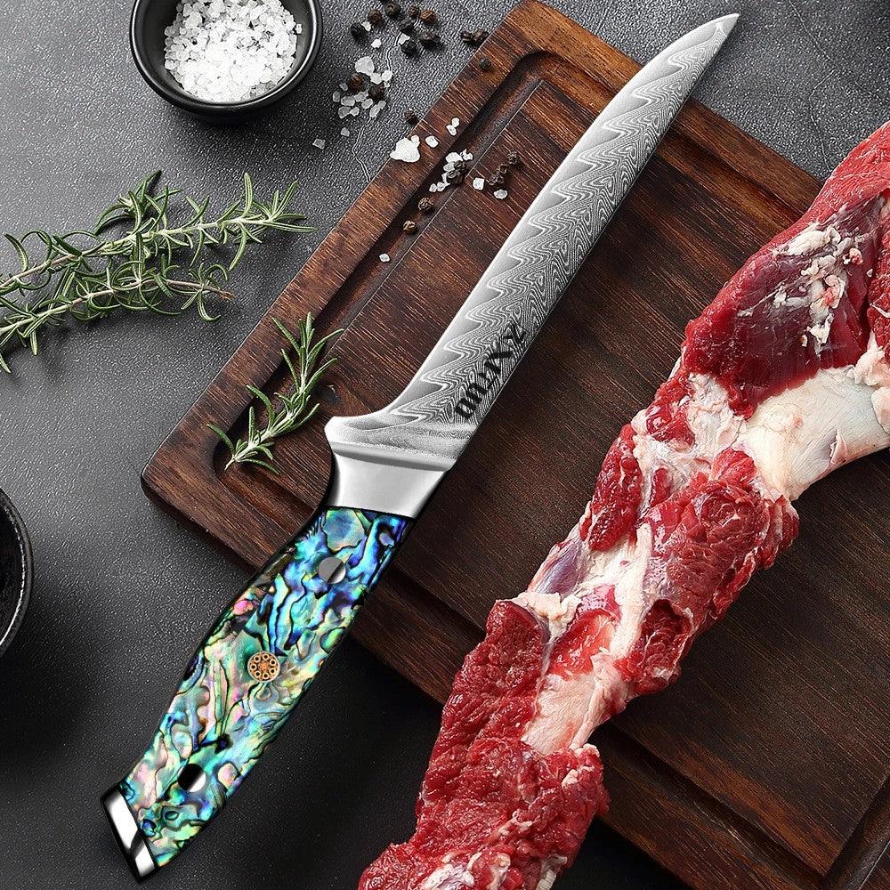 Damastmesser mit buntem Griff auf Holzbrett neben rohem Fleisch, Gewürzen und Kräutern