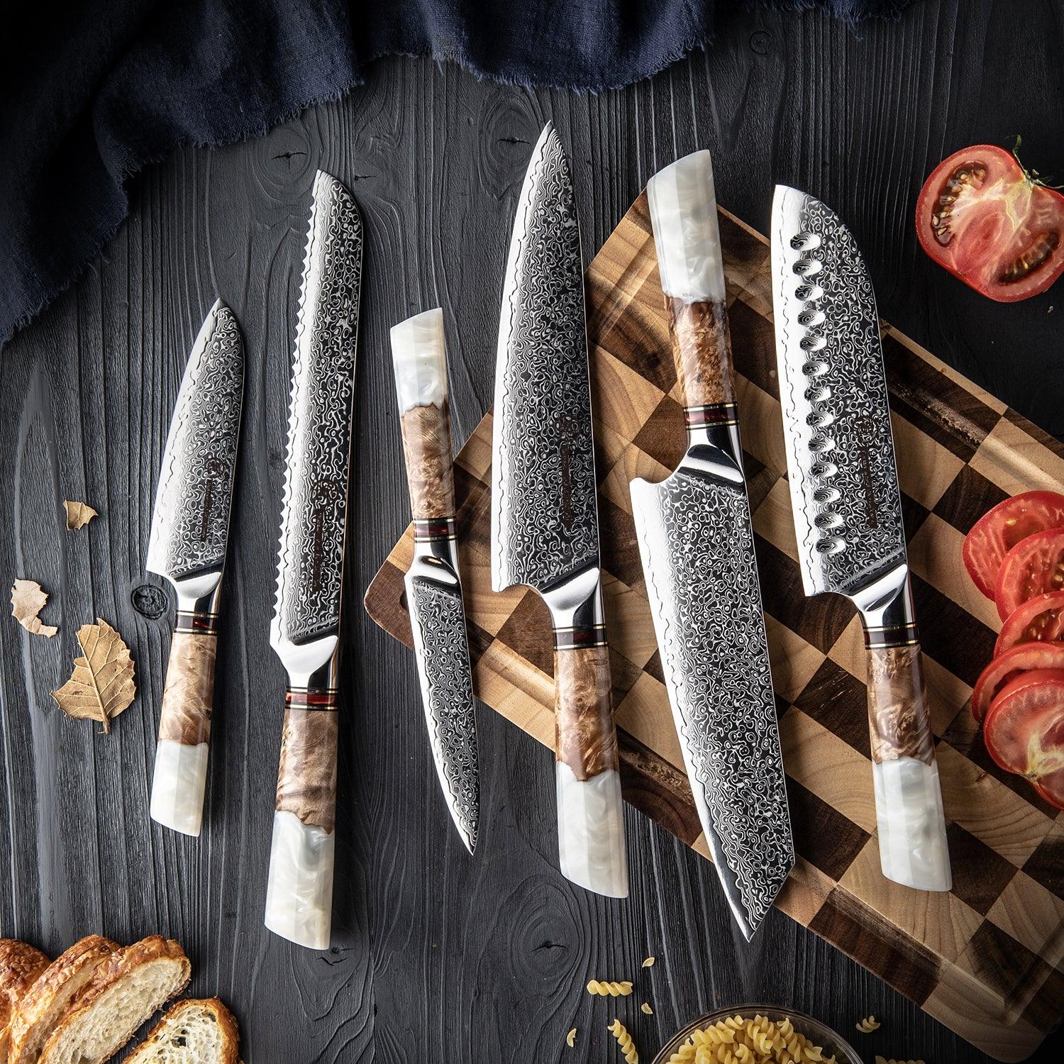 Damastmesser-Set mit weißem Harzgriff auf Holzbrett, Tomaten und Brot, edle Küchenutensilien