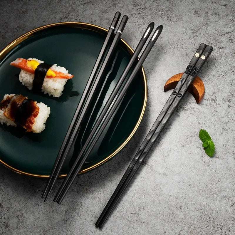 Schwarze Essstäbchen aus Metall auf grüner Teller mit Sushi, stilvolle Küchenaccessoires