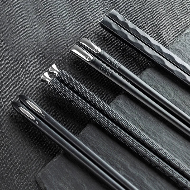 Moderne schwarze Essstäbchen aus Metall auf Schiefer, Küchenutensilien für stilvolles Kochen