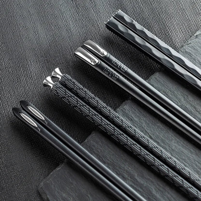 Moderne schwarze Essstäbchen aus Metall auf Schiefer, Küchenutensilien für stilvolles Kochen