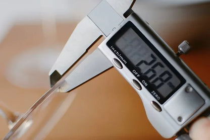 Digitale Schieblehre misst dünnen Rand eines hochwertigen Weinglases, Küchenaccessoire