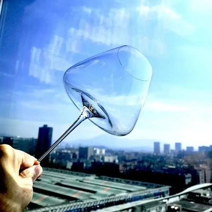 Hand hält elegantes Weinglas vor Stadtpanorama, Küchenutensilien von Kochschein