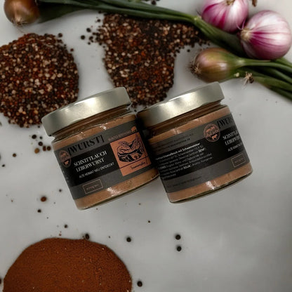 Zwei Gläser Schnittlauch-Leberwurst auf weißer Arbeitsplatte, mit Gewürzen, Frühlingszwiebeln und Schalotten – exklusive Küchenutensilien und Accessoires für stilvolles Kocherlebnis.
