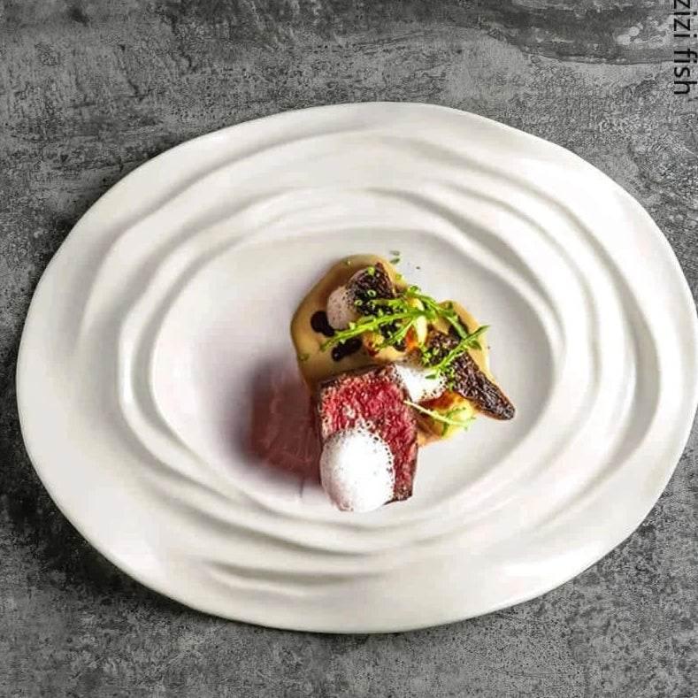 Exklusiver weißer Essteller mit Wellenstruktur und stilvoll angerichtetem Gourmetgericht