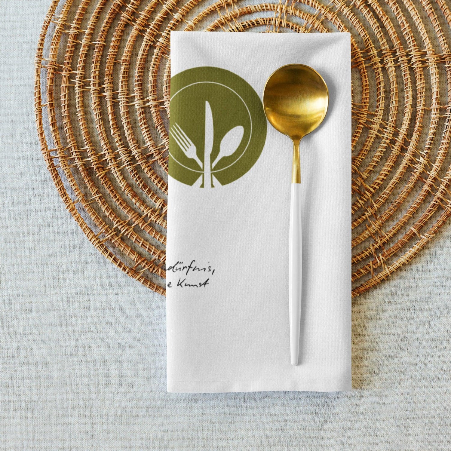 Weiße Stoffserviette mit goldenem Löffel auf geflochtenem Platzset, modernes Küchenaccessoire