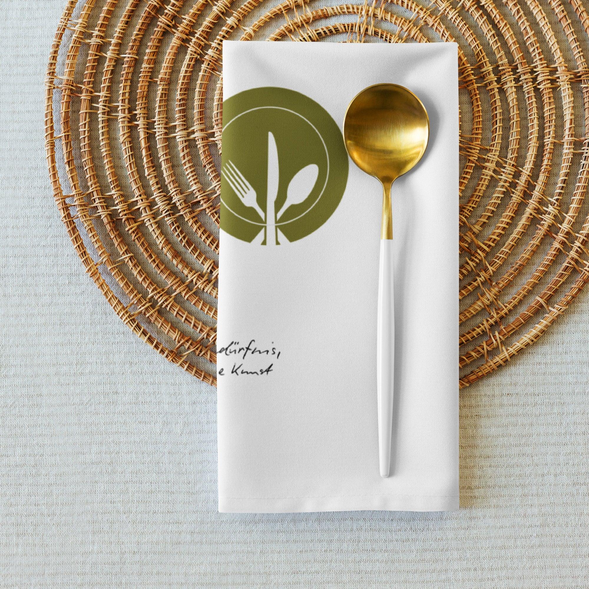 Weiße Stoffserviette mit goldenem Löffel auf geflochtenem Platzset, modernes Küchenaccessoire