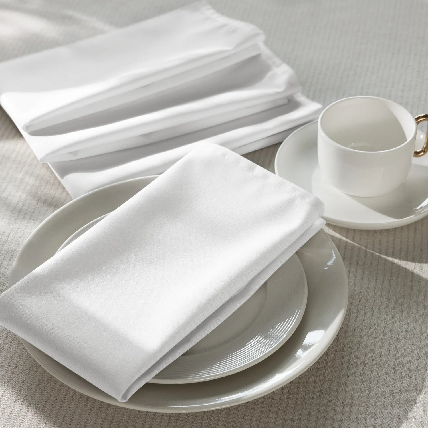 Weiße Stoffservietten Set, stilvoll arrangiert auf Porzellangeschirr und Tasse, Küchenaccessoire